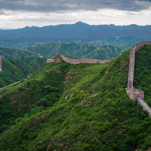 The Great Wall of China winding over green mountain ridges