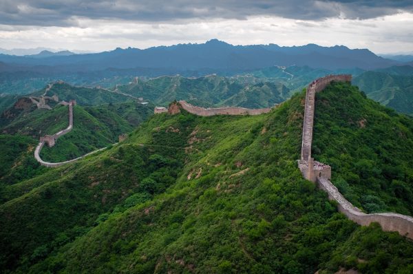 The Great Wall of China winding over green mountain ridges