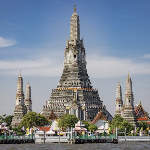 Wat Arun temple spires on the Chao Phraya River at sunset in Bangkok