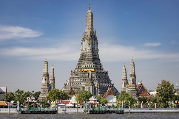 Wat Arun temple spires on the Chao Phraya River at sunset in Bangkok